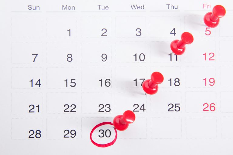 A black-and-white calendar page marked with red pushpins and a circled final date, representing the importance of building intentional, clear, realistic RFP timelines that support quality responses and informed decisions.