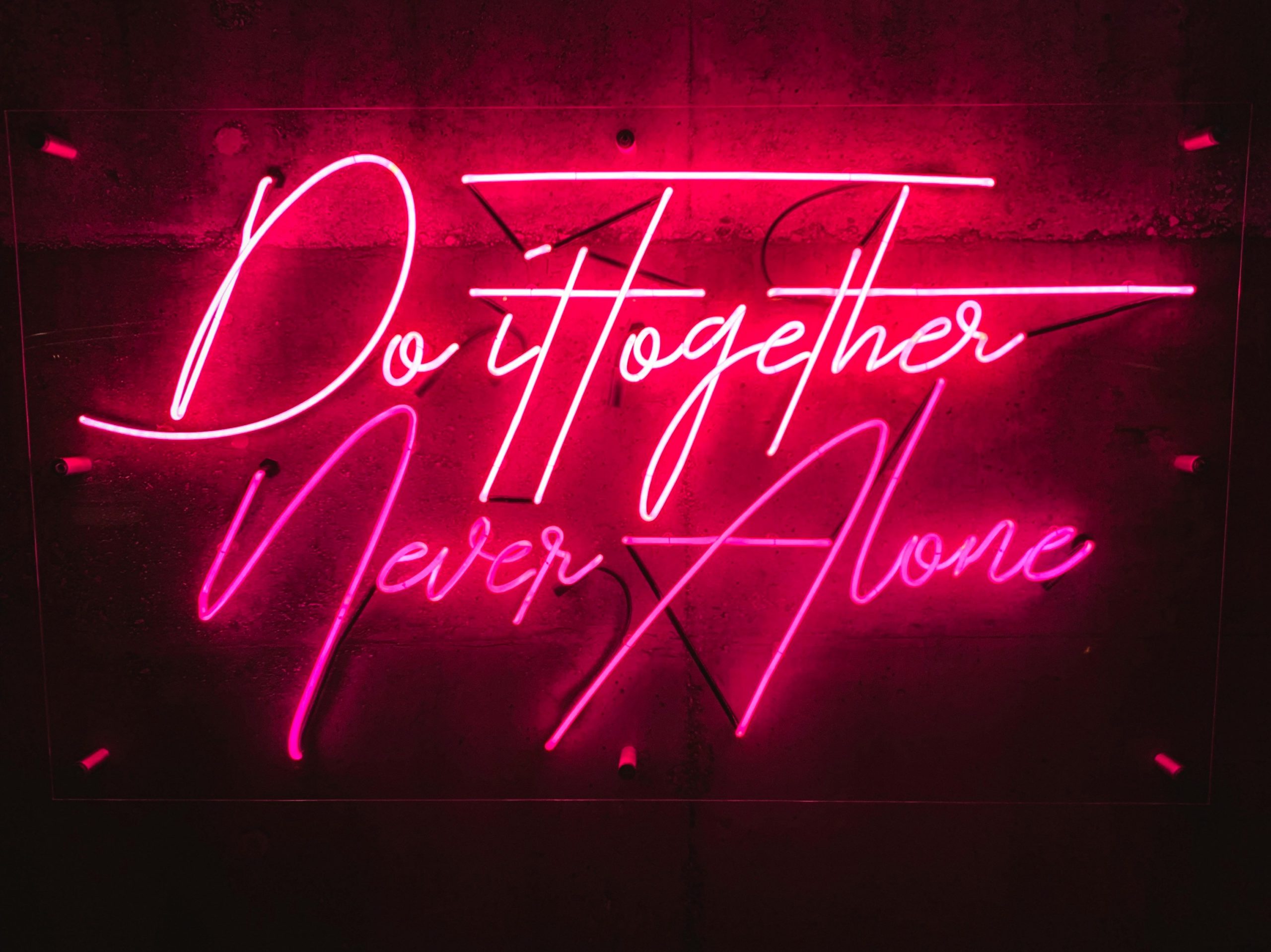 Red neon sign reading “Do it together, never alone” glowing against a dark background—underscoring that agency success depends on team chemistry and collaborative fit, not just résumés.