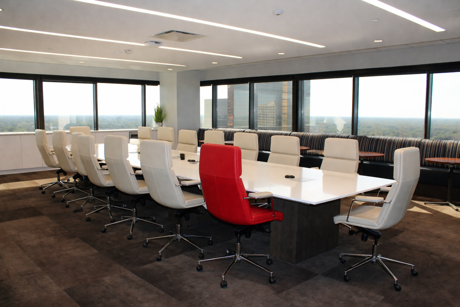 Modern boardroom with one red chair among white chairs, symbolizing structured dissent in executive decision-making.