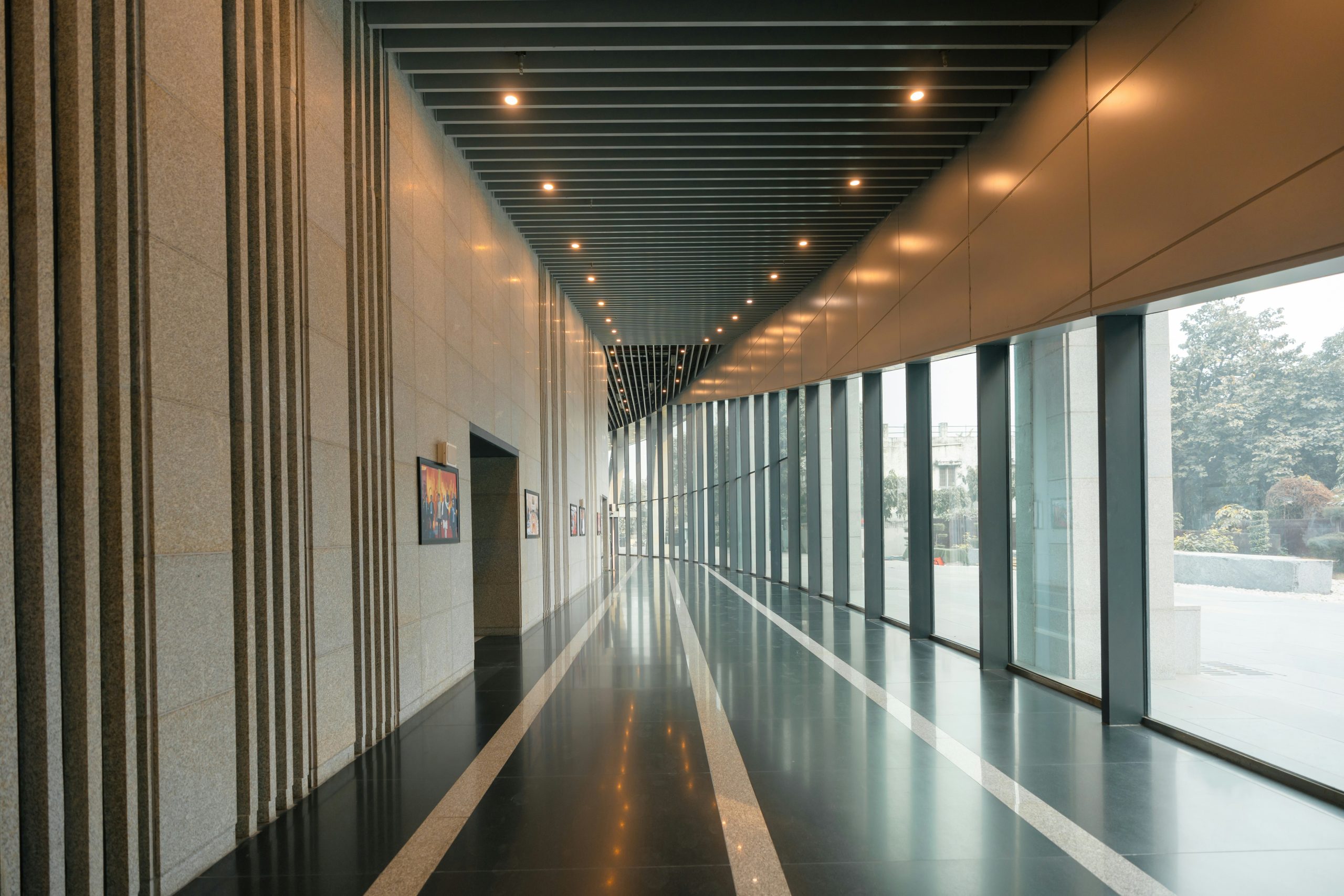 Empty corporate corridor with floor-to-ceiling windows, representing the leadership and talent gaps created by over-reliance on AI efficiency.